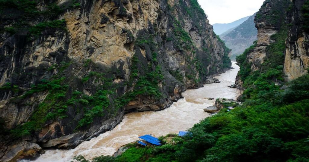 "Steep cliffs and the rushing waters of Tiger Leaping Gorge, surrounded by towering mountains."