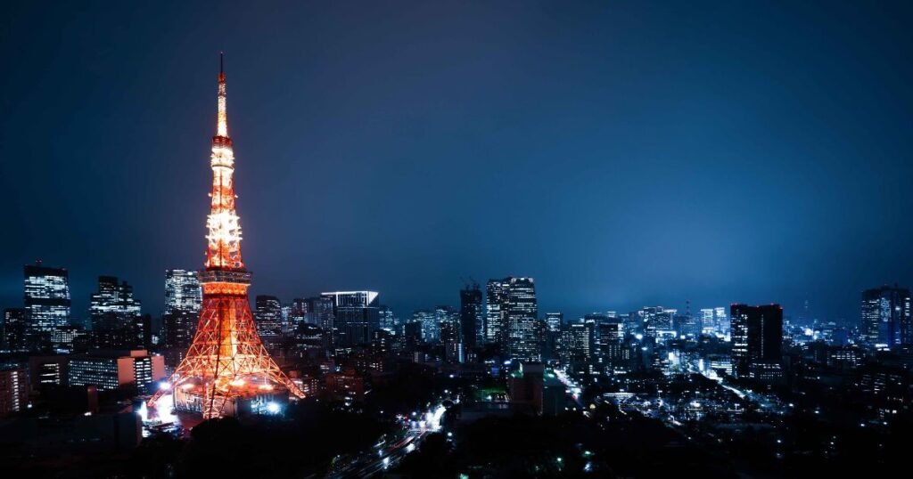 "Tokyo Tower illuminated at night, with the sprawling city skyline in the background."