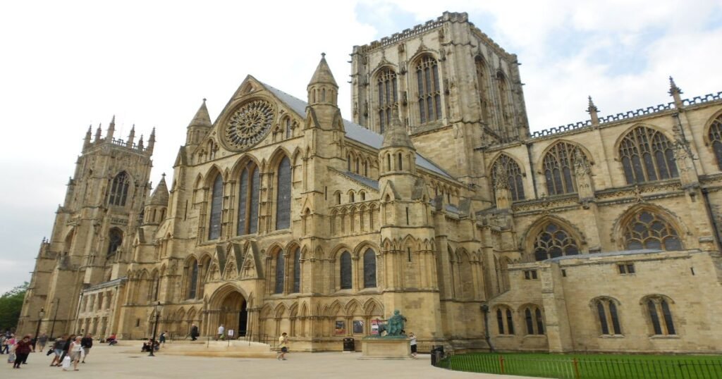 “York Minster, a grand Gothic cathedral with soaring towers and intricate stained glass windows, bathed in evening light.”