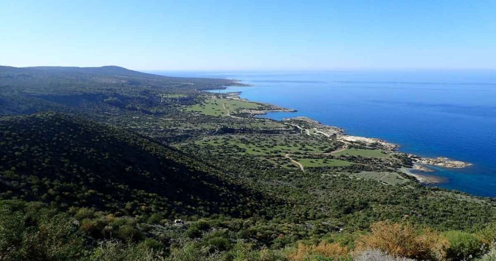 "Aerial view of the rugged coastline of Akamas Peninsula National Park, with crystal-clear waters and rocky cliffs."