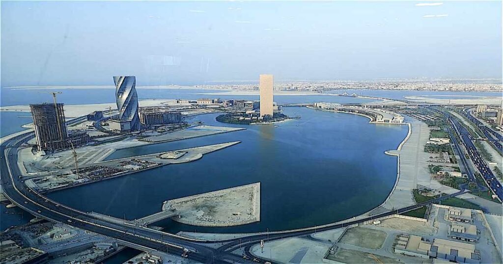 “Modern skyline and waterfront views at Bahrain Bay, with kayaks in the calm water.”