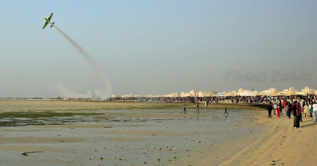 Sandy shores of Busaiteen Beach with Bahrain’s skyline in the distance.