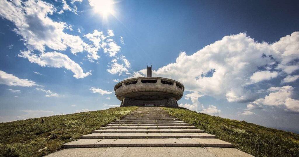 "The UFO-like Buzludzha Monument atop a mountain with a cloudy sky."