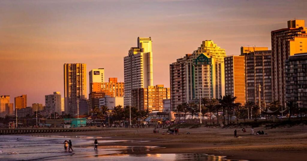 "Golden Mile beachfront in Durban with sunbathers and surfers enjoying the waves."