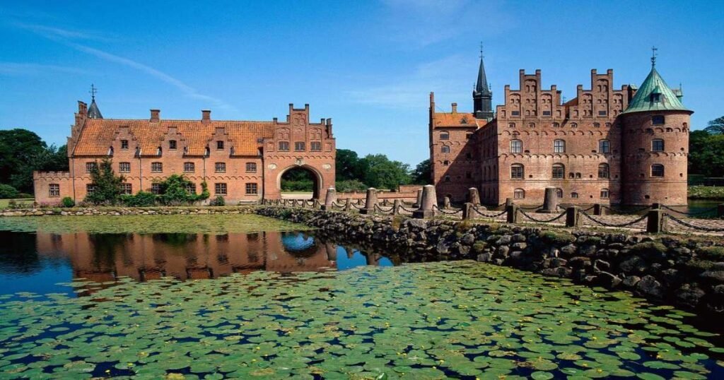 "View of Egeskov Castle and its reflection in the surrounding moat on Funen Island, Denmark."