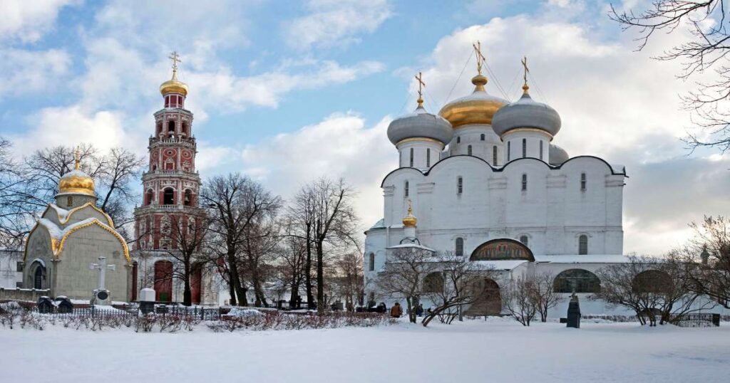 “Red-and-white towers and domes of the Novodevichy Convent reflecting in a tranquil pond.”