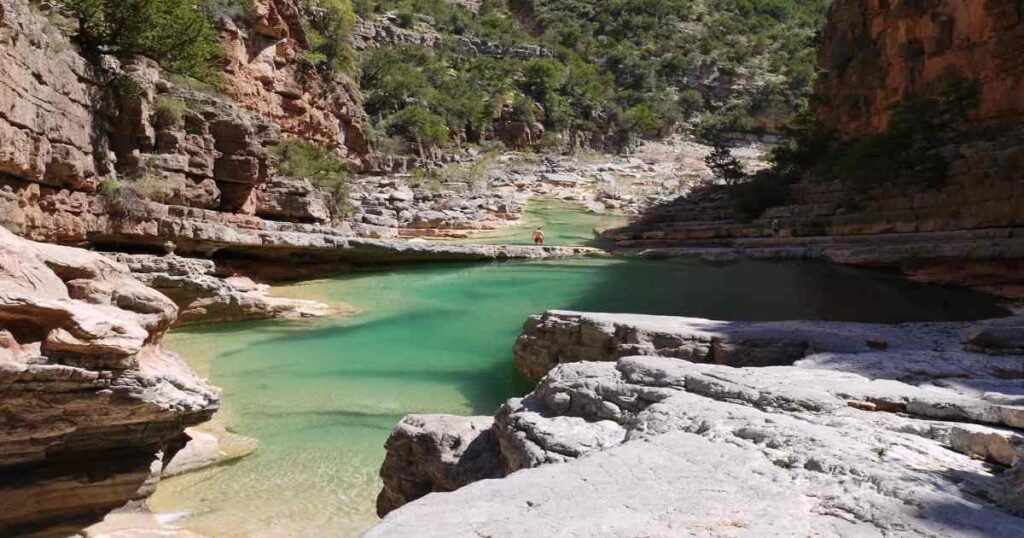 “Turquoise pools surrounded by palm trees and rocky cliffs in Paradise Valley.”