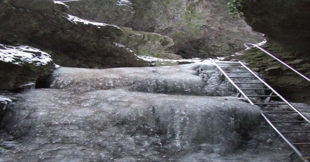 “Hikers ascending metal ladders through the narrow Rám Gorge with rocky walls towering on both sides.”