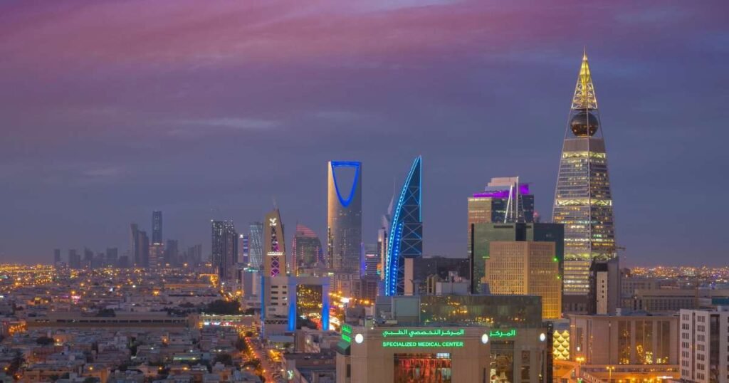 "The skyline of Riyadh featuring the Kingdom Centre Tower and other modern buildings against a sunset backdrop."