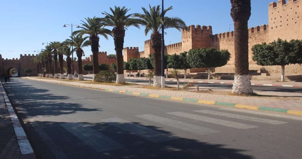 "Sunlit adobe walls surrounding the ancient town of Taroudant with mountains in the distance."