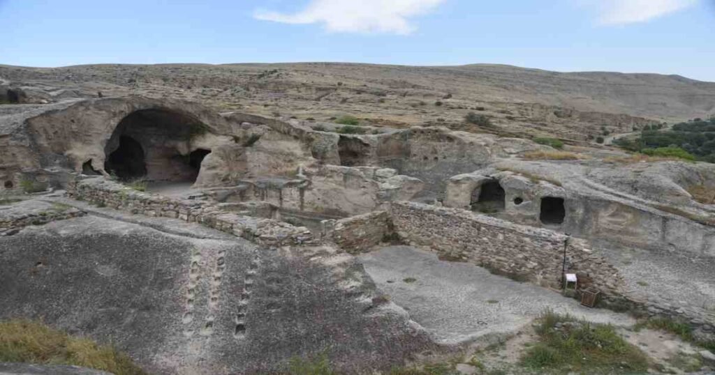 "Uplistsikhe Cave Town carved into rocky cliffs with pathways and ancient structures."