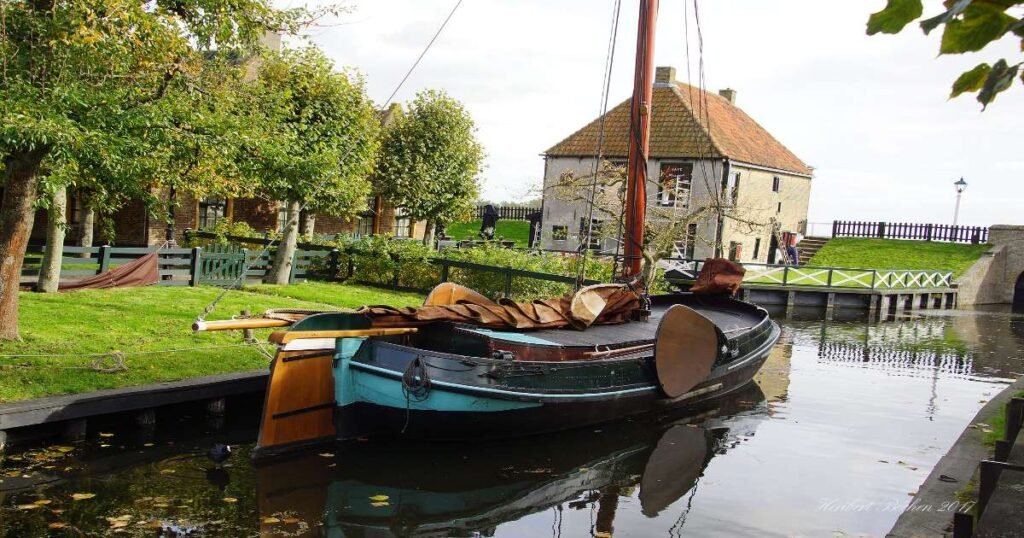 “Reconstructed historic village at Zuiderzee Museum, with traditional wooden houses and boats along the water.”