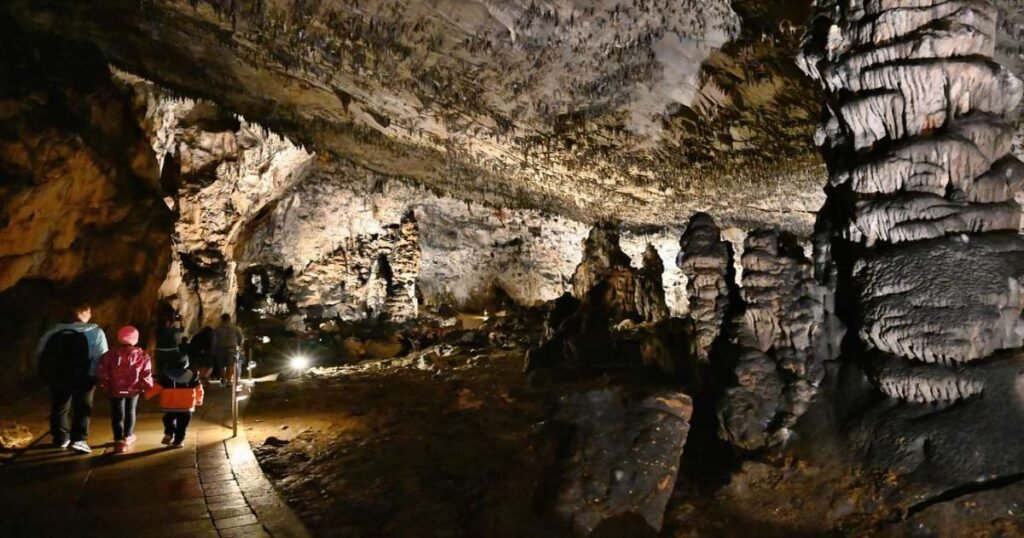 “Baradla Cave’s limestone formations illuminated by light, showcasing a grand underground hall.”