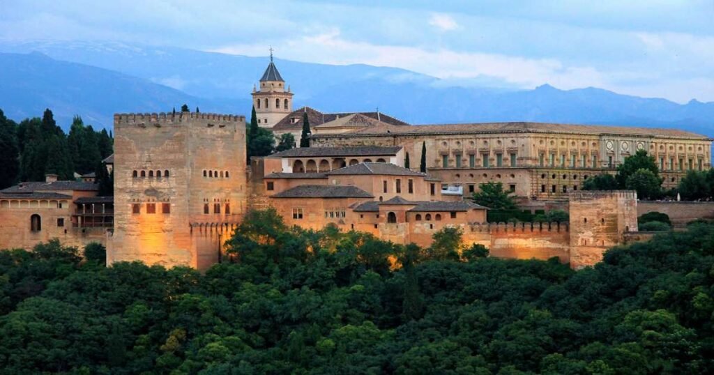 The Alhambra with its intricate architecture and lush gardens against a mountain backdrop.