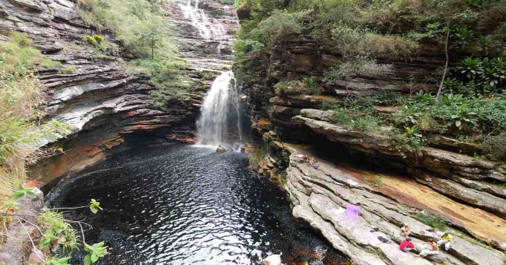 "A waterfall cascading into a clear pool surrounded by lush vegetation in Chapada Diamantina."