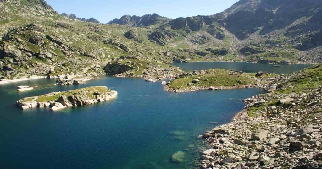 “Clear blue waters of Juclar Lakes surrounded by rugged mountain peaks and rocky terrain.”