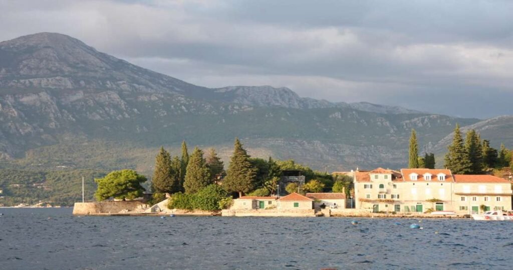 “Crystal-clear waters and rocky coastline of Lustica Peninsula with olive trees in the background.”