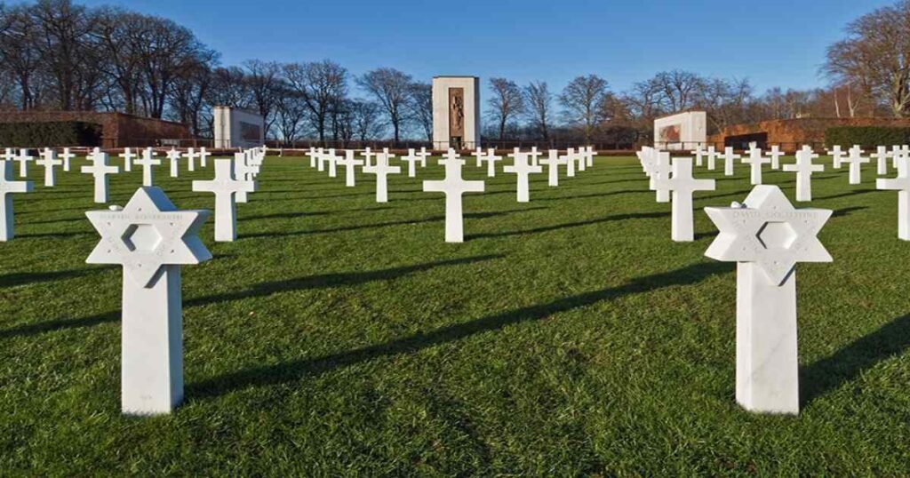 "Rows of white gravestones at Luxembourg American Cemetery with a memorial in the background."