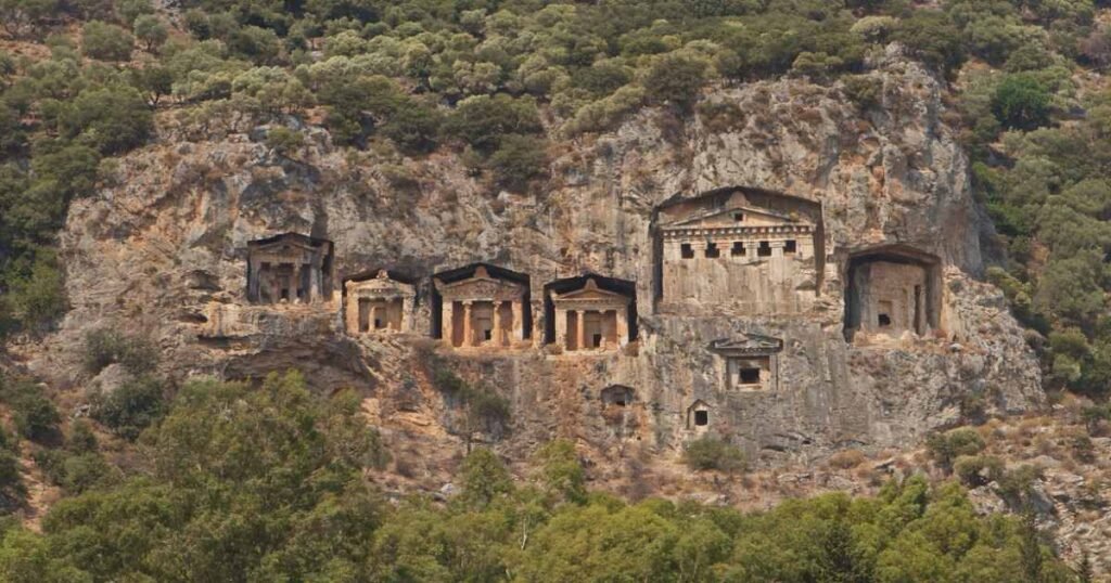Lycian rock tombs carved into cliffs above the Dalyan River at sunset.