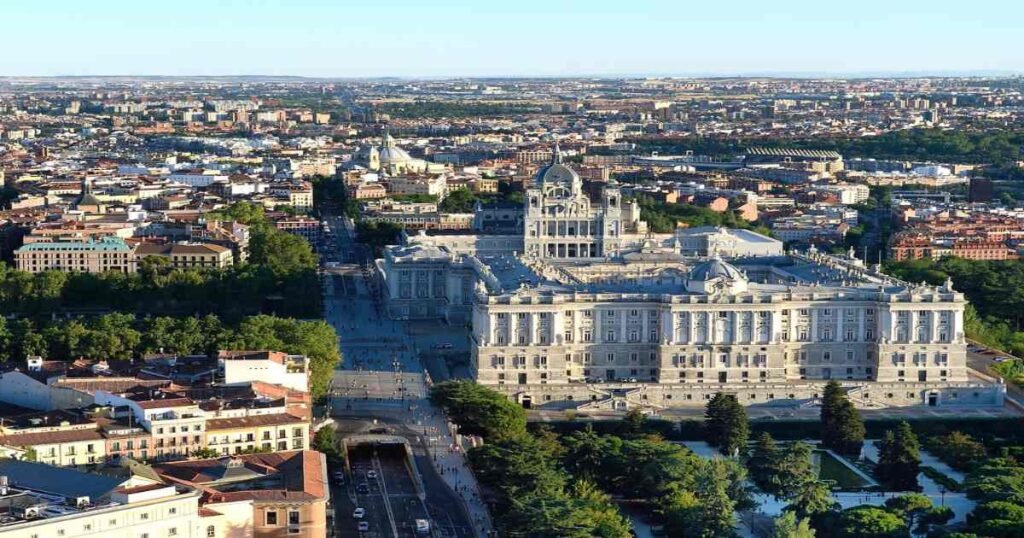 "Aerial view of the Royal Palace of Madrid with its stately architecture and surrounding area."