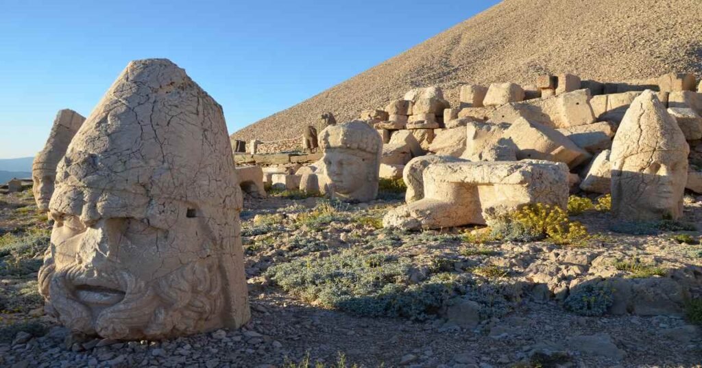 Giant stone heads on Mount Nemrut illuminated by the golden light of sunrise.