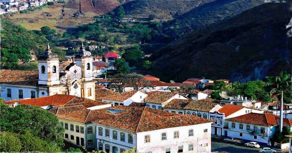 "Panoramic view of the colonial buildings and cobbled streets in Ouro Preto under a bright blue sky."