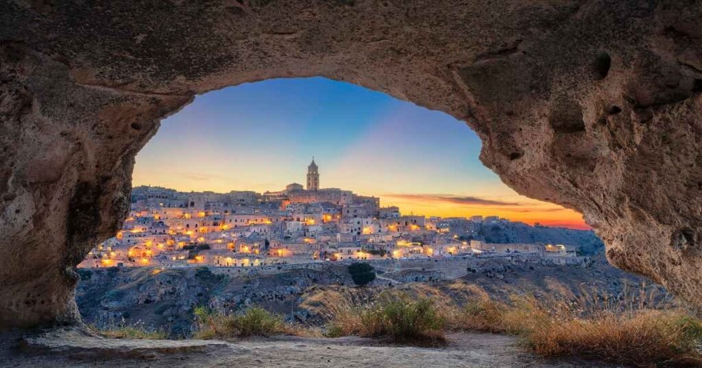 The ancient cave dwellings of Matera illuminated at night, creating a magical glow.