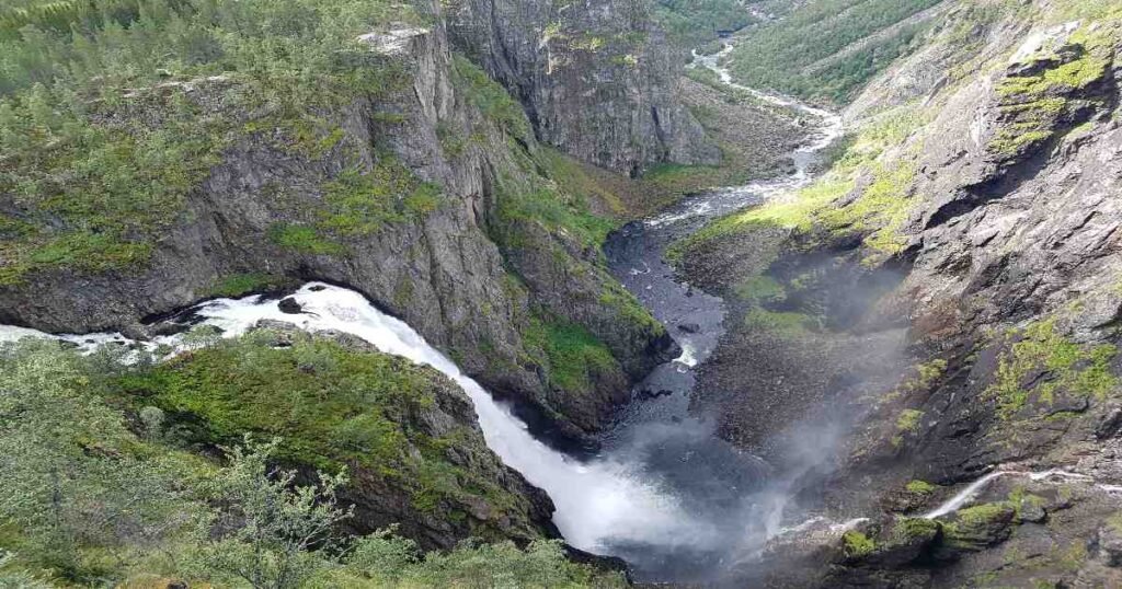 “Vøringfossen waterfall cascading into a deep gorge surrounded by green cliffs.”