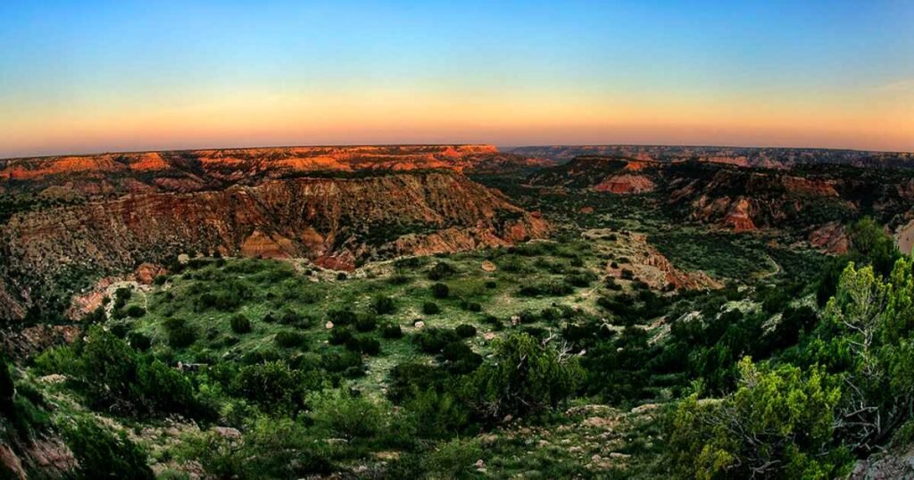 The striking red rock formations of Palo Duro Canyon under a clear blue sky.