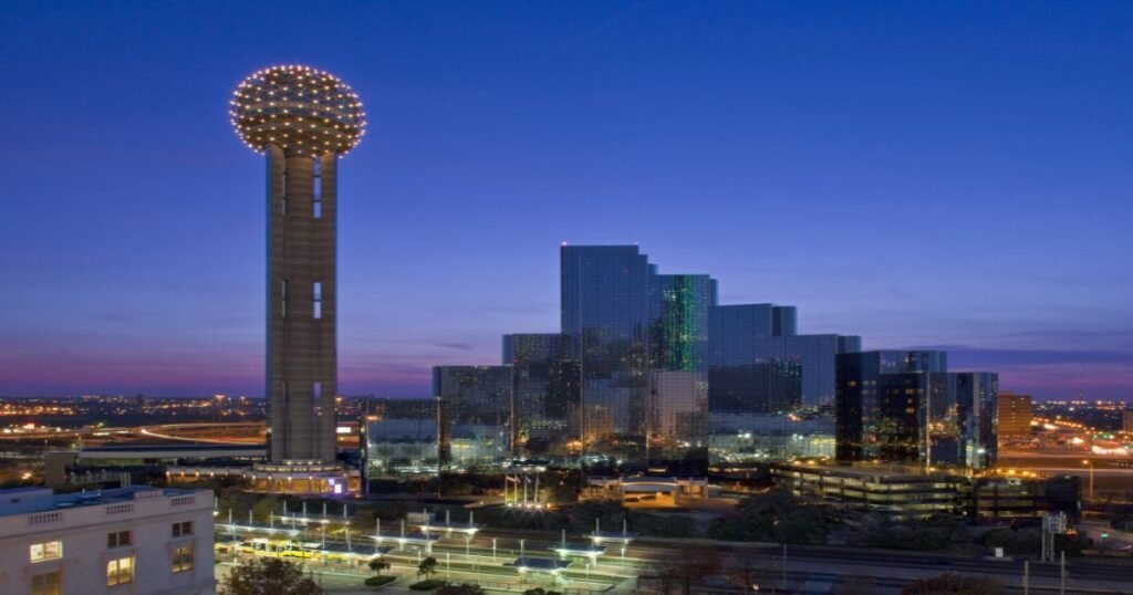 Reunion Tower glowing against the Dallas skyline at night.