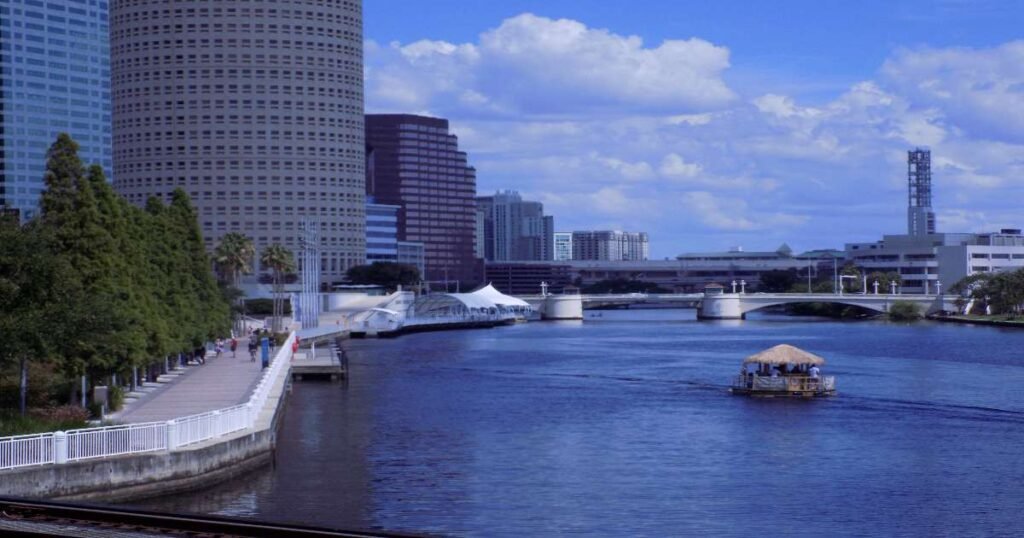 Tampa Riverwalk at sunset with lit bridges and cityscape in the background.