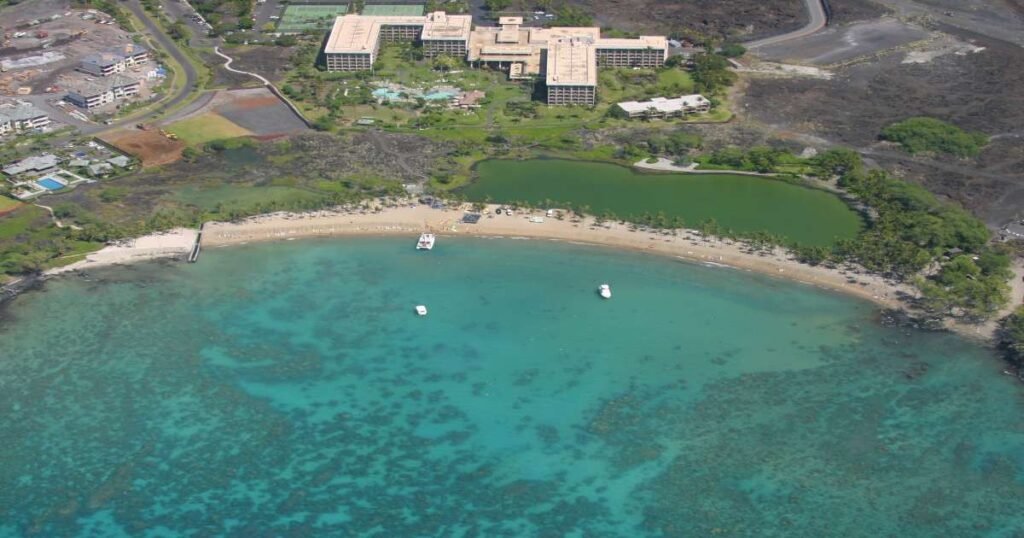 Aerial view of the Golden sands and swaying palm trees at Anaehoʻomalu Beach.