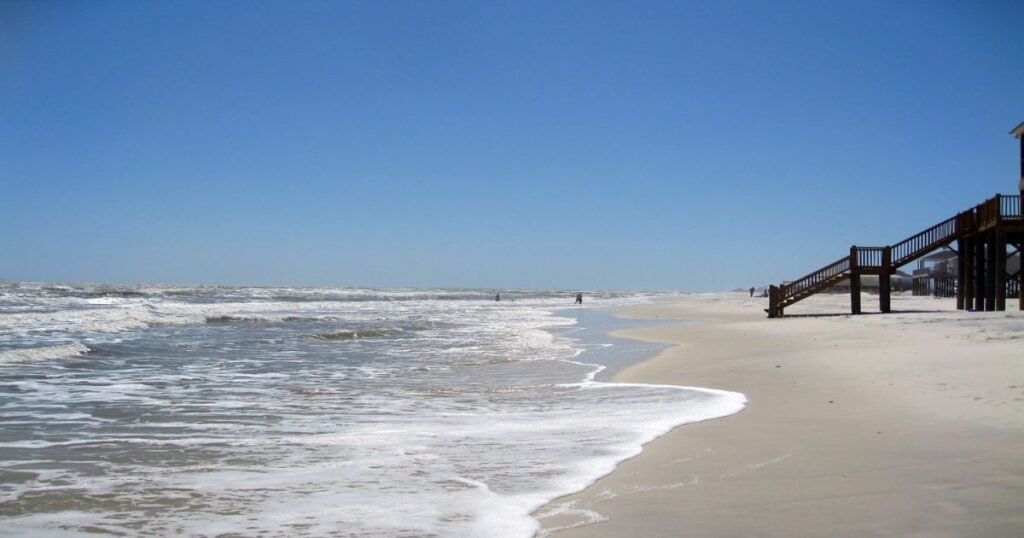 A serene beach on Dauphin Island with gentle waves and golden sand.
