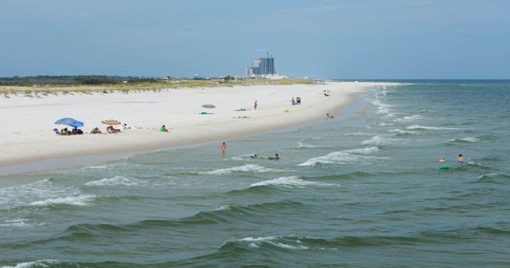 A sunny day at Gulf Shores Beach with turquoise waves and white sand.